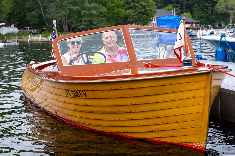 A smiling couple aboard their varnished classic boat at the Naples docks
